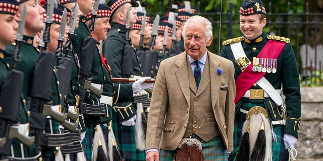 King Charles in traditional Scottish clothing being greeted by locals