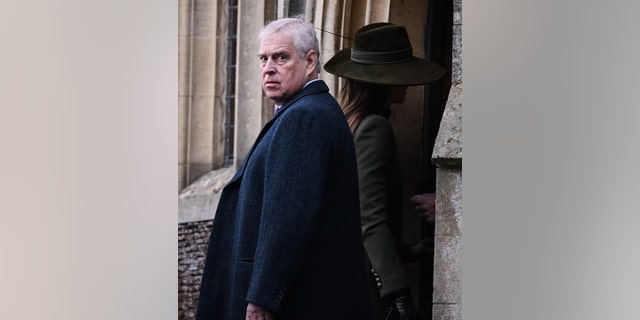 Prince Andrew looks directly back at the camera in a long coat while Kate Middleton walks inside in a green hat and coat