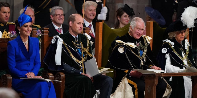 Kate Middleton in a blue dress sitting next to Prince William, King Charles and Queen Camilla
