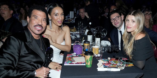 Lionel Richie at the Rock & Roll Hall of Fame ceremony with his girlfriend Lisa Parigi in a white dress and they sit across from Sofia Richie and her now-husband Elliot Grainge
