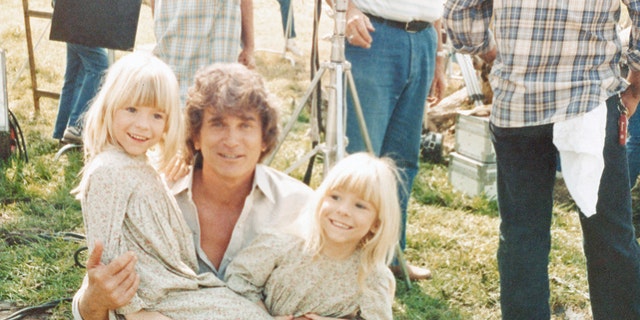 Wendi Lou Lee and her twin sister in costume smiling while being held by Michael Landon