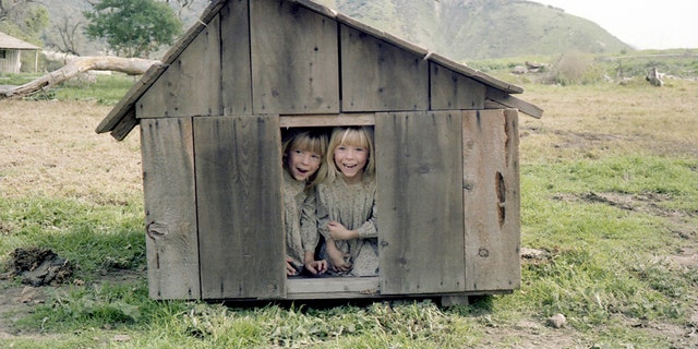 Wendi Lou Lee and her twin sister Brenda in costume inside a wooden dog house