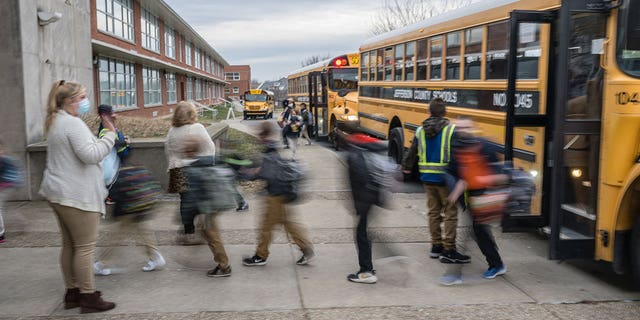 teacher waves to her students near buses