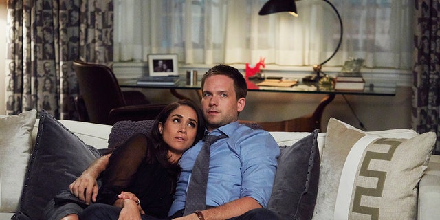 Meghan Markle sitting on the couch with Patrick J. Adams in a scene from Suits