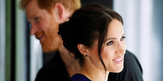 A close-up of Meghan Markle and Prince Harry facing opposite directions from each other
