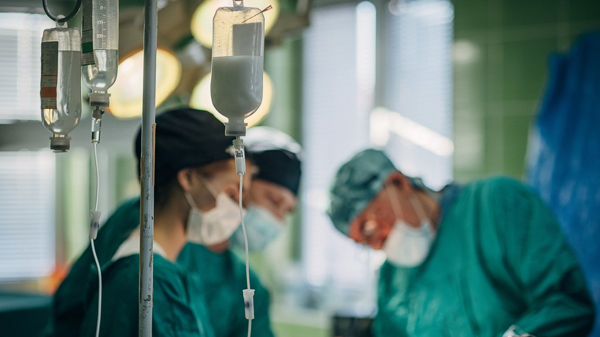 Stock photo of surgical team operating in full gowns and masks