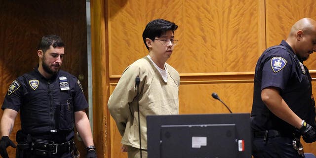 Alleged rapist doctor Zhi Alan Cheng in handcuffs is led into a courtroom