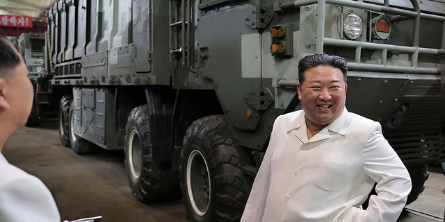 Kim near a heavily armored vehicle