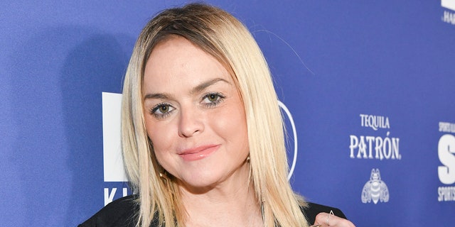 Taryn Manning with bright blonde hair in a black shirt tilts her head slightly to the right on the carpet