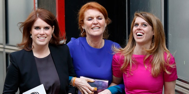 Sarah Ferguson wearing a blue dress in the arms of her two daughters as they all laugh