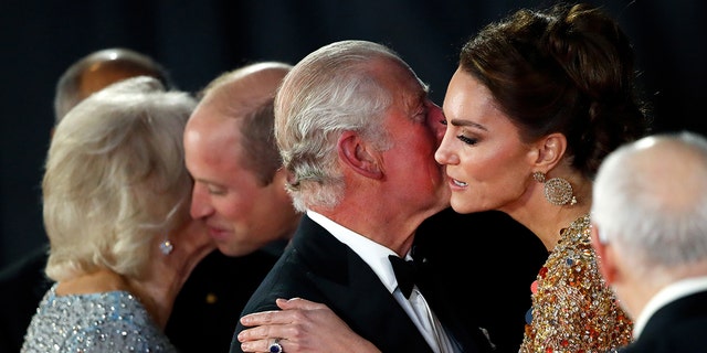 Kate Middleton in a gold gown being kissed on the cheek by King Charles