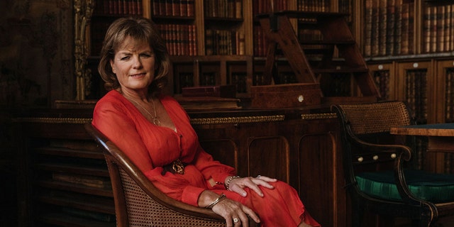 Emma, Duchess of Rutland wearing a red dress and sitting on a couch