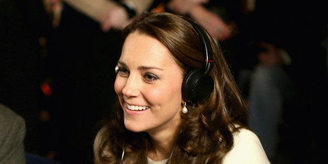 A close-up of Kate Middleton wearing a white sweater and headphones