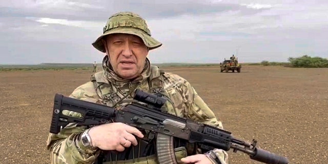 Prigozhin in military fatigues holding a weapon