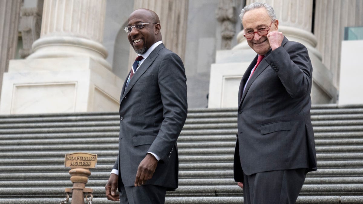 Senators Raphael Warnock and Chuck Schumer on the steps of the Capitol building