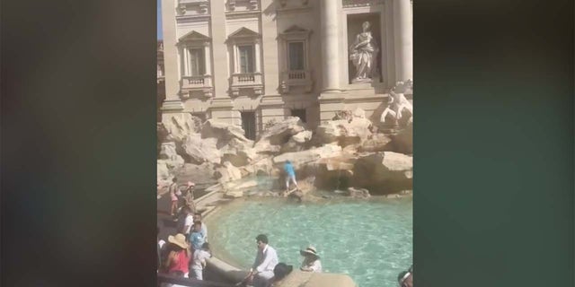 Tourist fills water bottle at Trevi Fountain