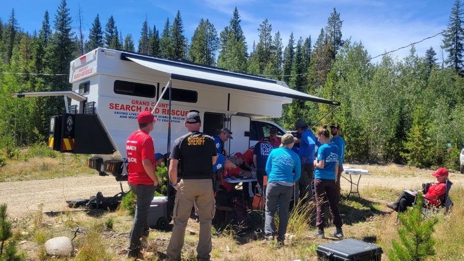 A search-and-rescue crew gathers near a camper