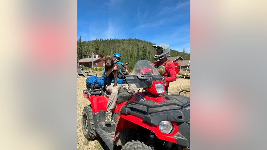 Two search-and-rescue officials are pictured on a four-wheeler with a search dog