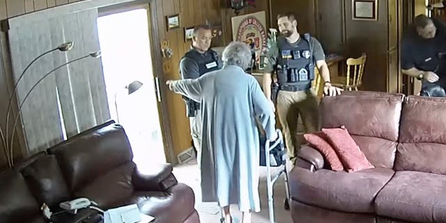 Joan Meyer gestures at officers in her living room, ordering them to get out of her house