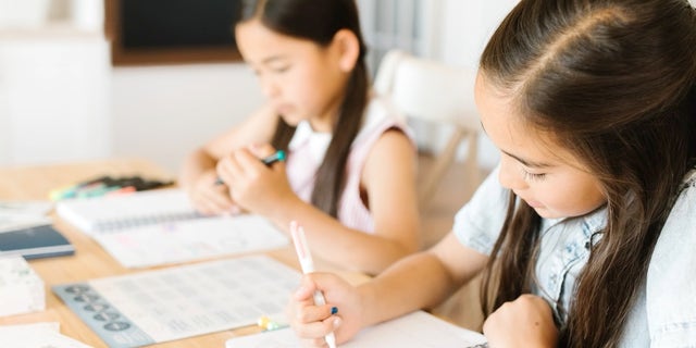 Homeschool kids writing in notebooks