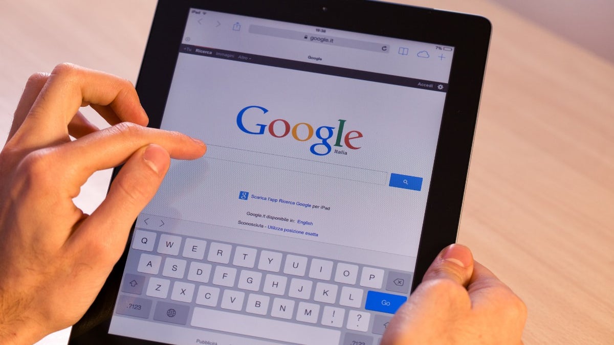 Person holds their iPad with the Google search page on the screen