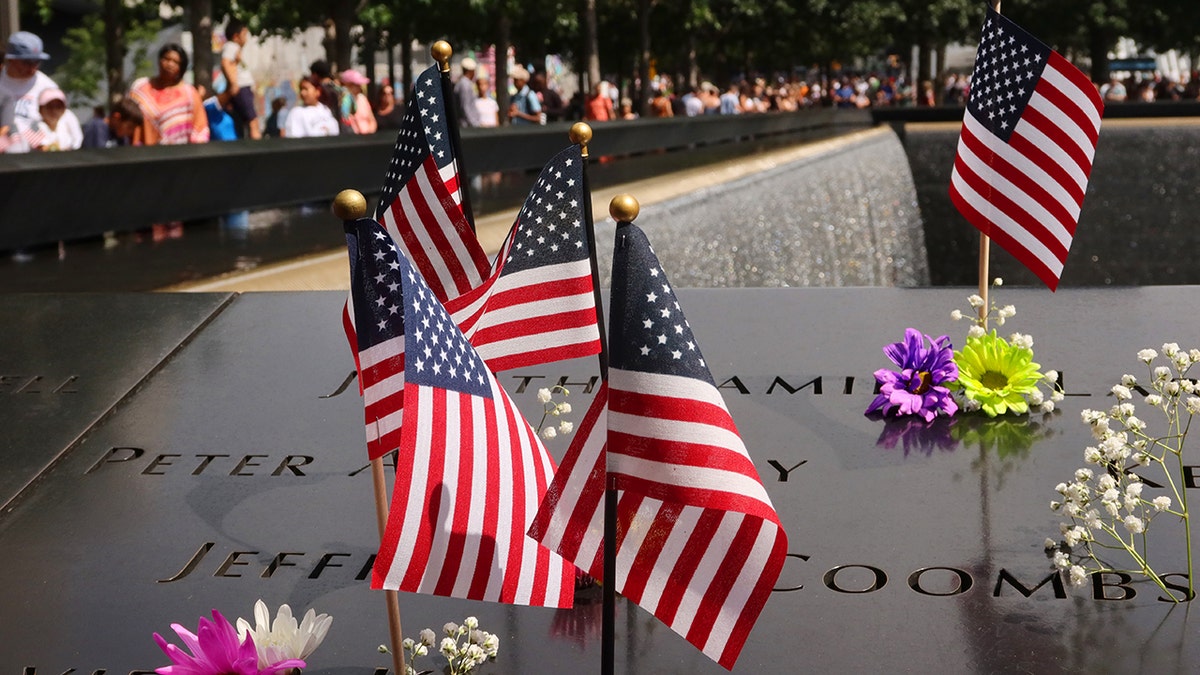 9/11 Memorial in New York City covered with American flags and flowers