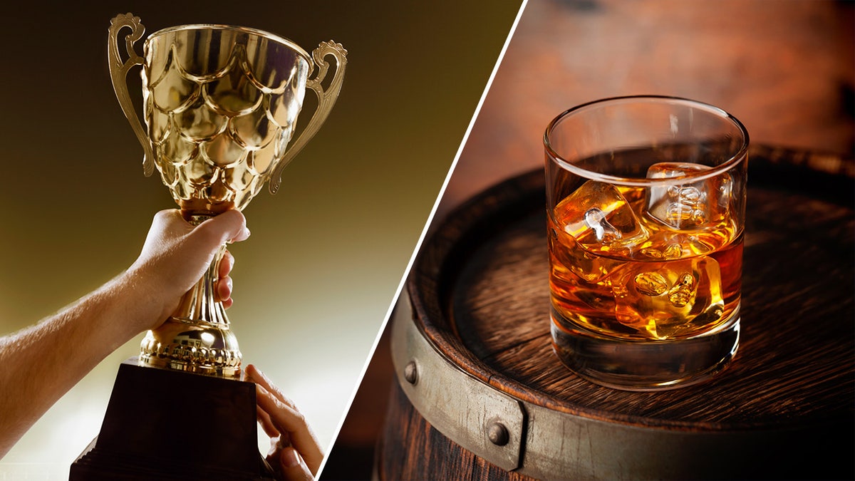 hand holding trophy in air and whiskey glass 