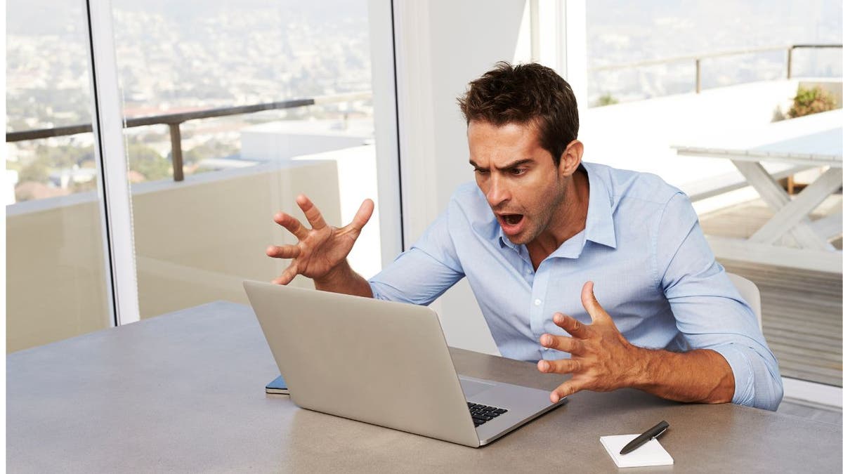 Man looking at his laptop with a shocked face.