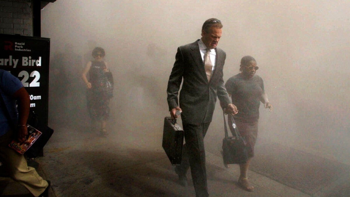 man in suit with suitcase walks thru dusty street on 9/11