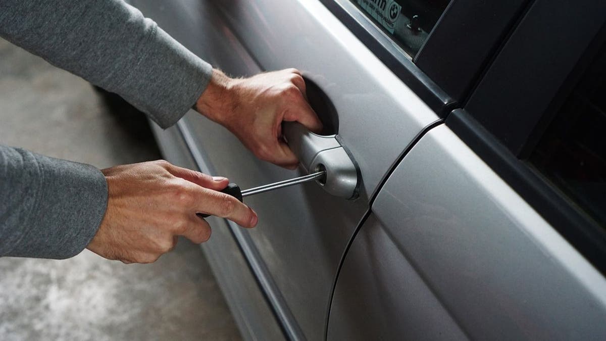 Person's hand using a tool to open locked car door