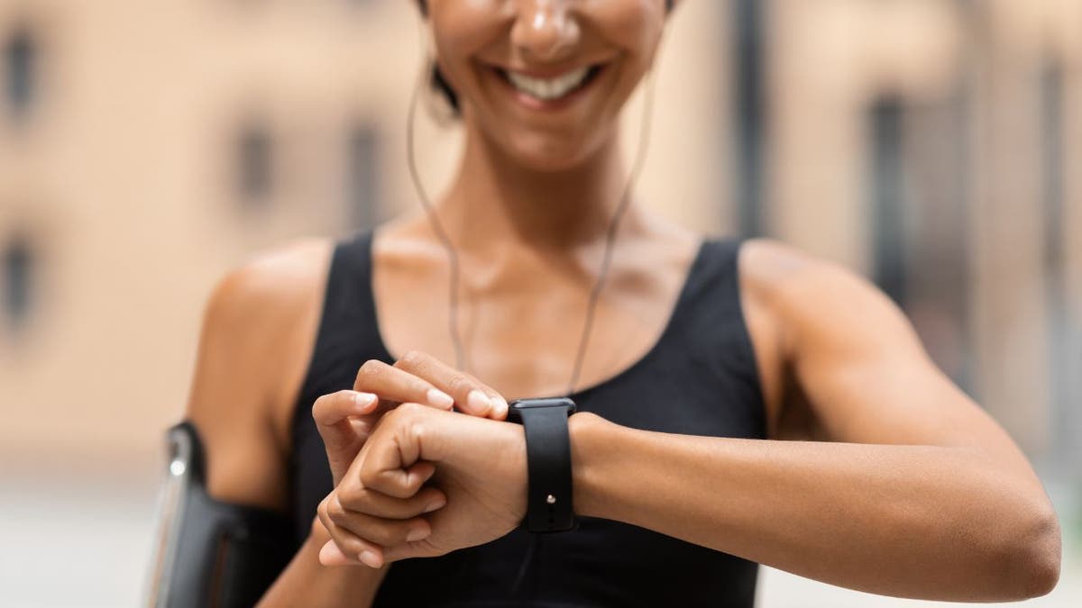 Stock image shows woman checking a fitness tracker on wrist