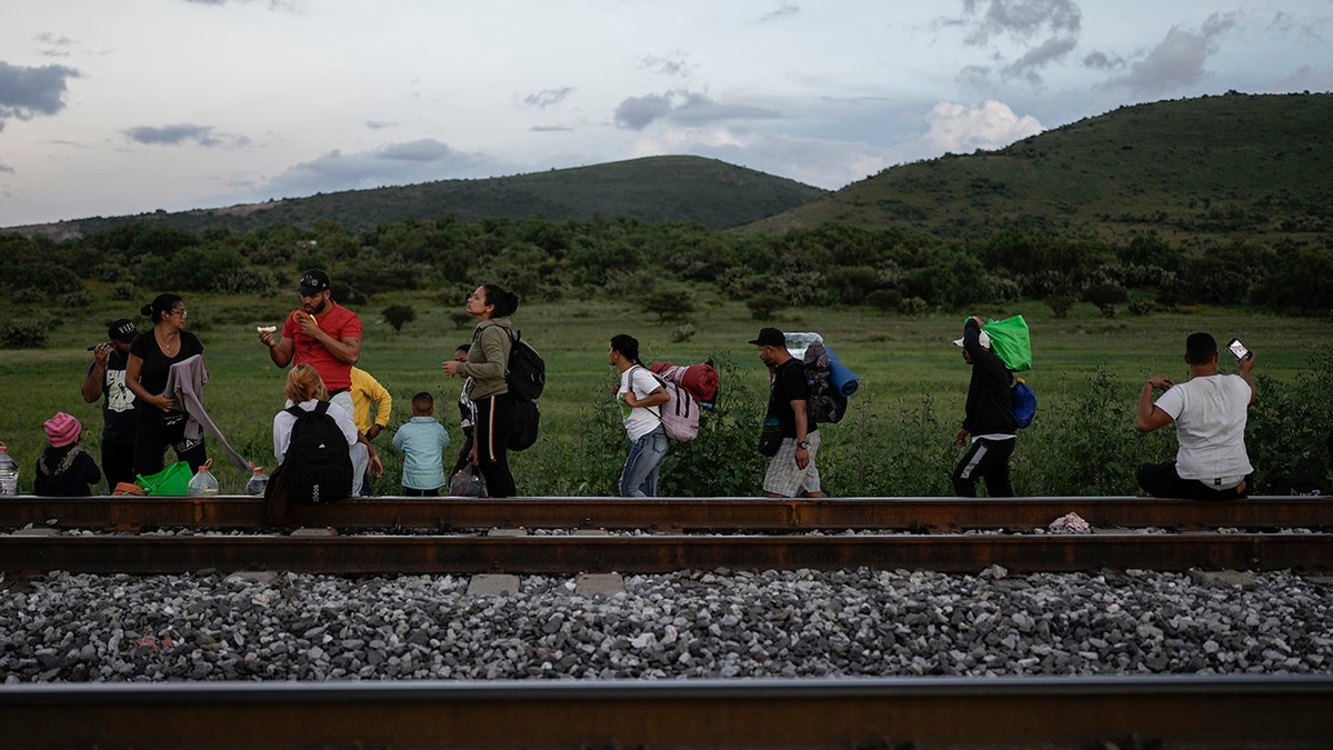 People with backpacks, train, a hill