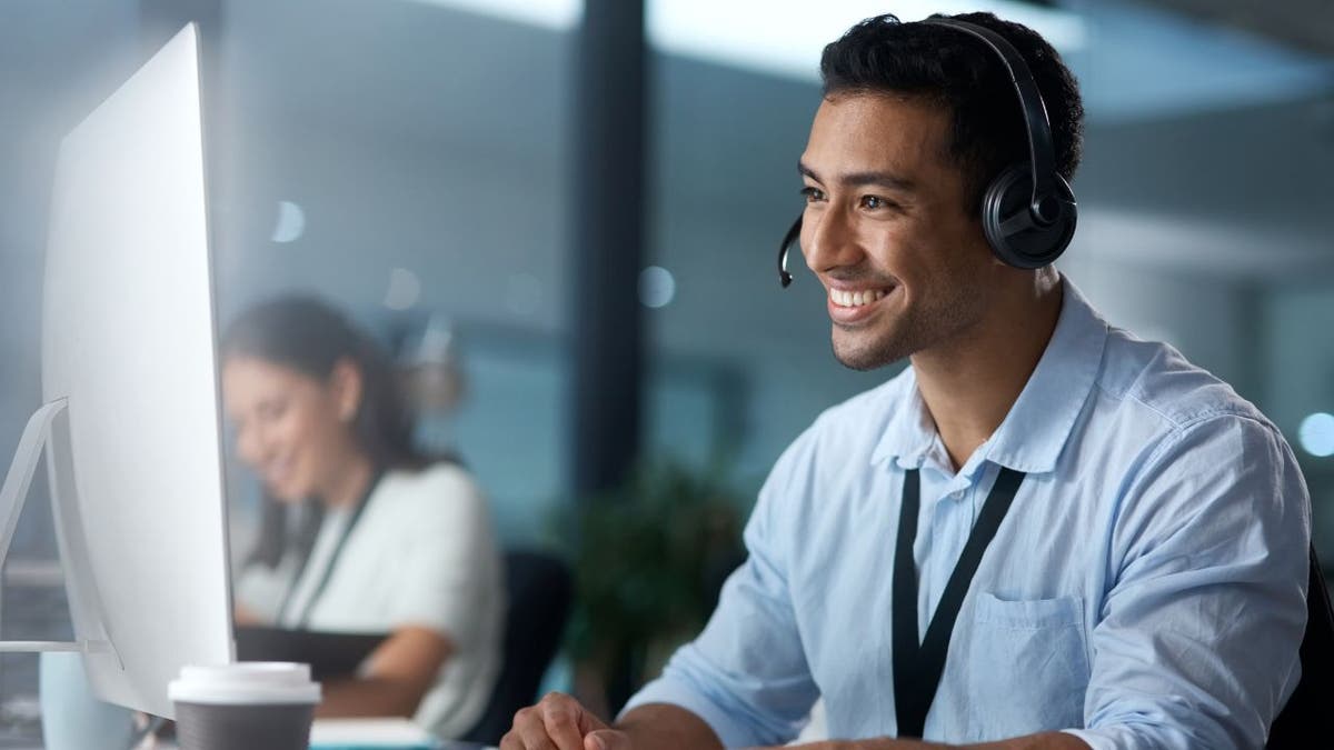 Man wearing a headset, smiling at his computer.