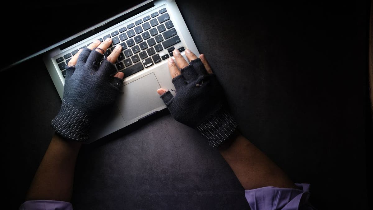 Hands on a laptop in a dark room.