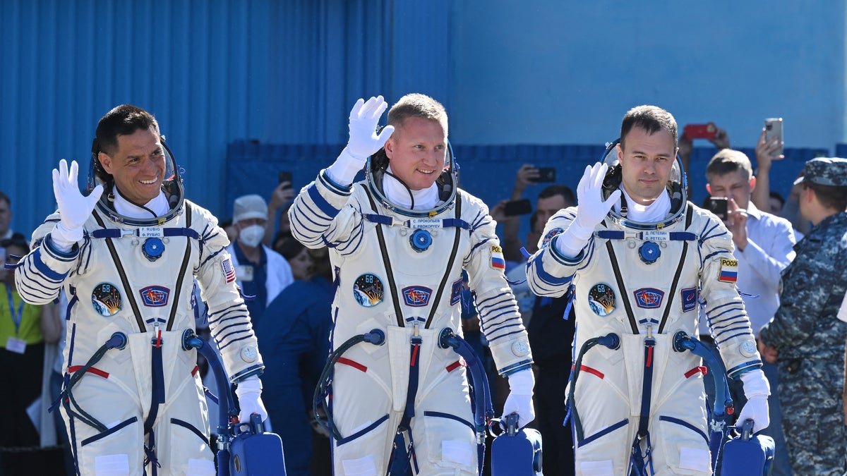 Frank Rubio and his Russian cosmonaut team members in space suits waving to the press.