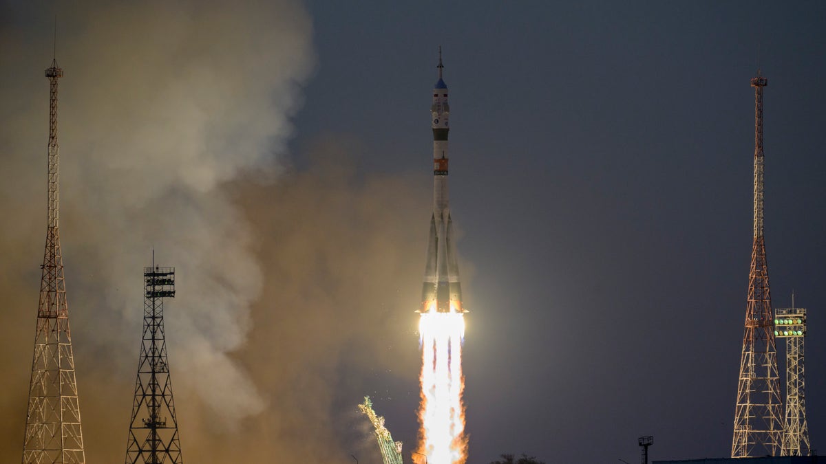 A Russian Soyuz rocket moments after launching with fire emerging from the tail lighting up a dark sky.