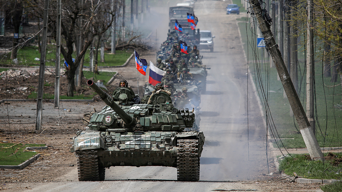 Russian military talks driving down a road in Ukraine in single file line