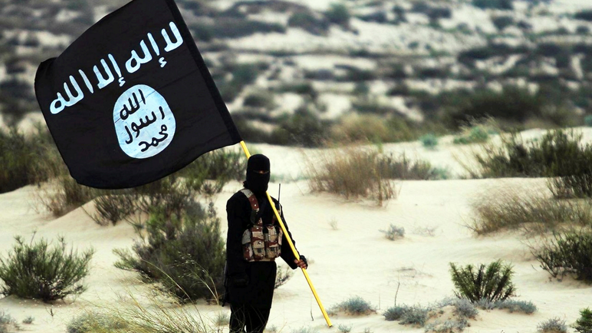 Islamic State militant holds ISIS flag in a desert setting