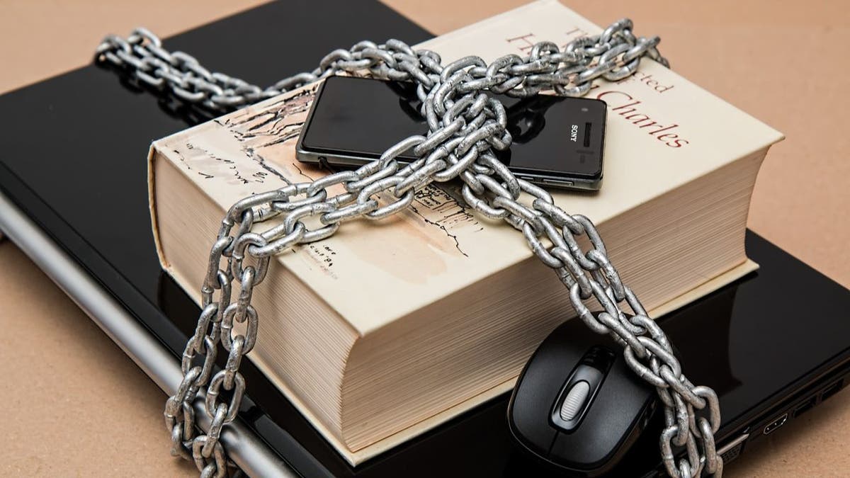 chains wrap around a laptop, book, and phone together