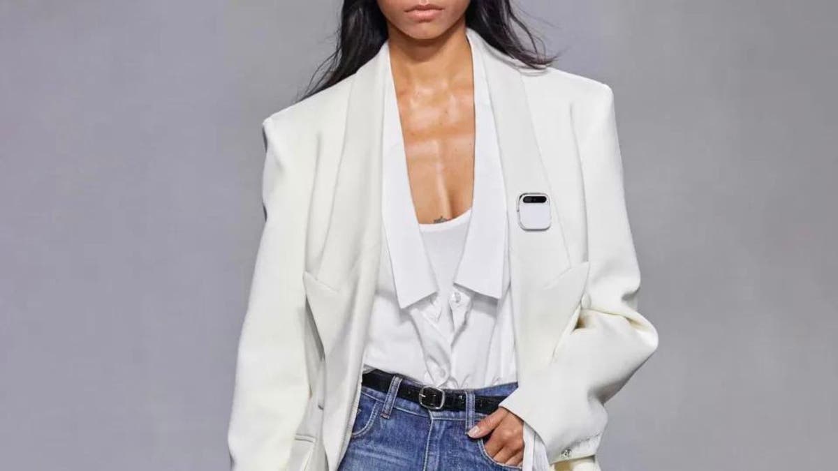 Naomi Campbell wearing the AI Pin with a white outfit.