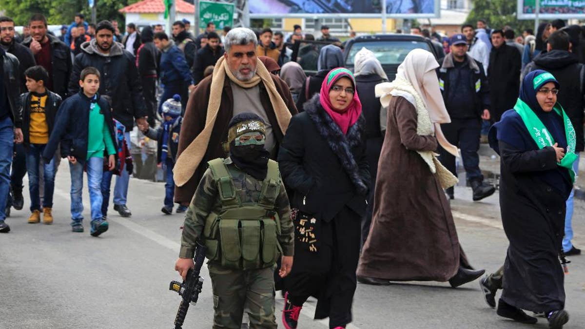 A masked Palestinian boy wears a uniform and holds a toy weapon during a rally to commemorate the 29th anniversary of the founding of Hamas, in Gaza City, Wednesday, Dec. 14, 2016. Tens of thousands of Palestinians, including hundreds of gunmen, rallied in Gaza in support of the militant Islamic group Hamas that rules the territory. Hamas overtook Gaza by force in 2007 after routing troops loyal to Palestinian President Mahmoud Abbas in bloody street battles. Palestinians have been divided since between Gaza under Hamas and Abbas governing parts of the West Bank. (AP Photo/Adel Hana)