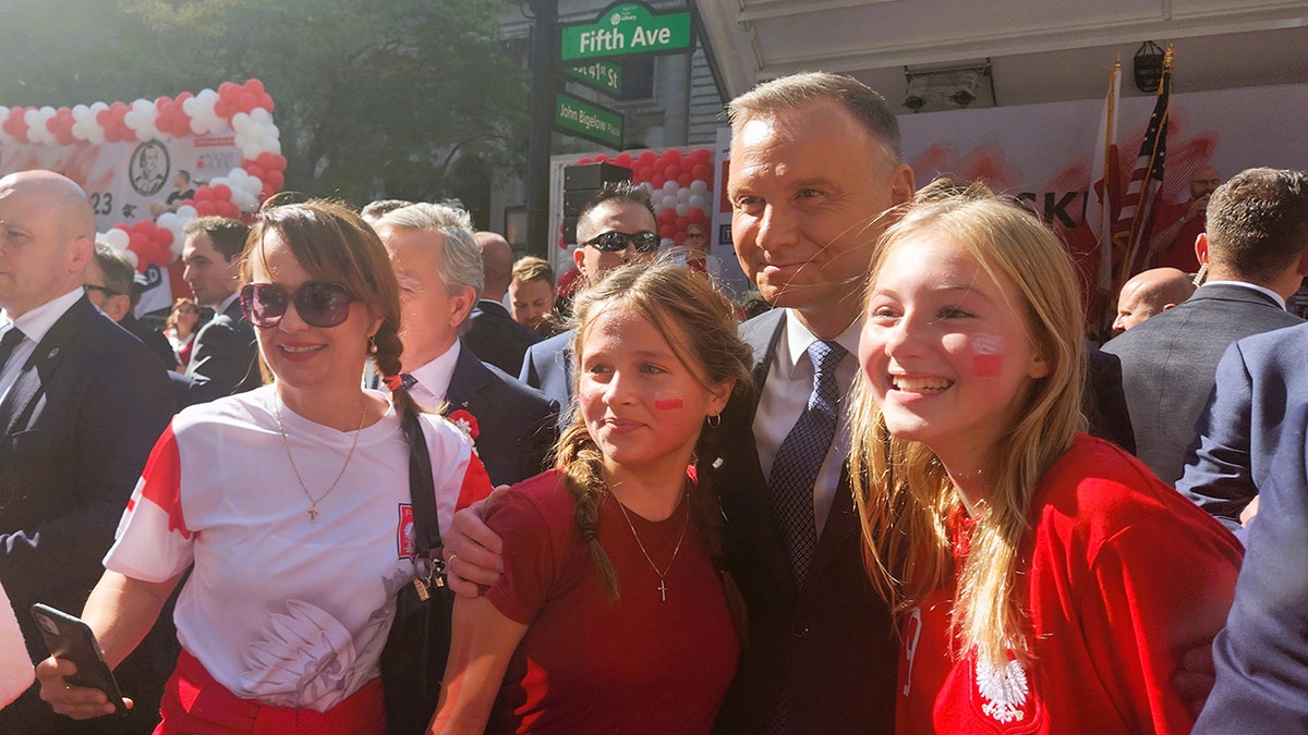 President Duda pictured smiling with two girls and a woman at the Pulaski Day Parade