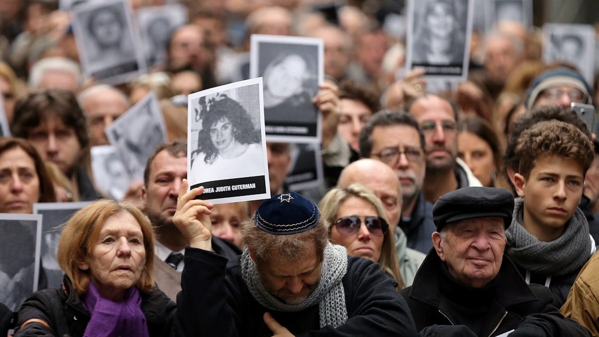 People holds images of those killed in the 1994 bombing of a Jewish community center in Argentina