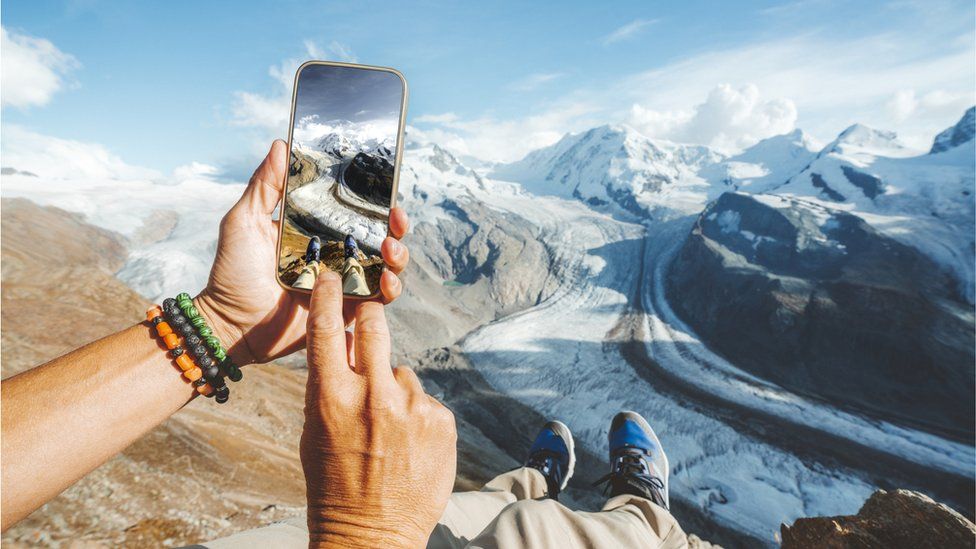 A person taking a photo of snowy mountains