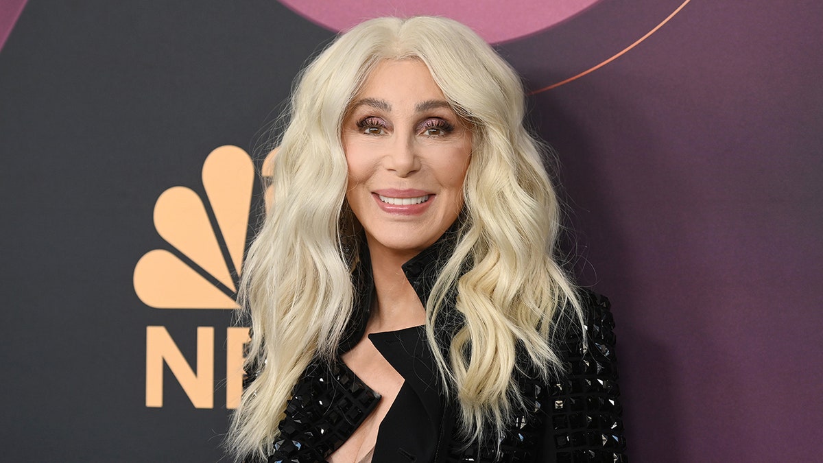 Cher with blonde hair smiling on the red carpet