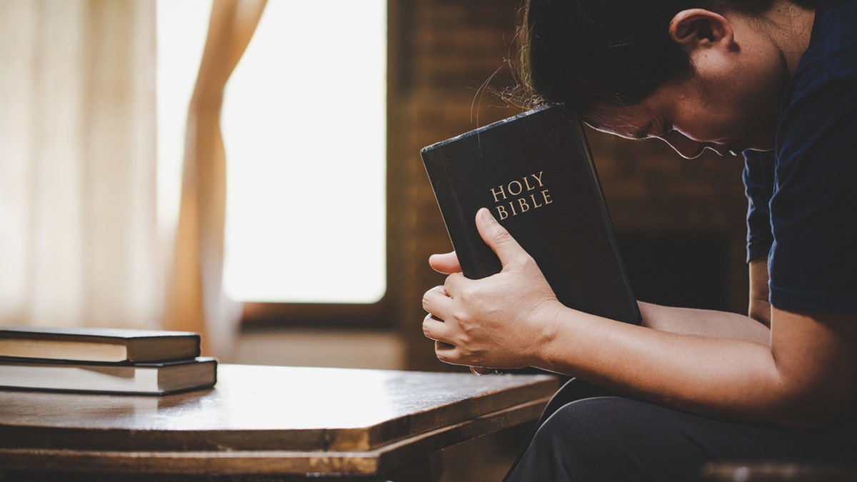 person praying with bible in hands