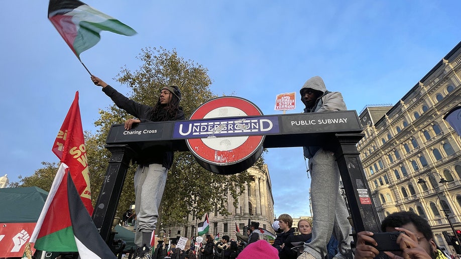 Protesters hold Palestinian flags near a London underground sign