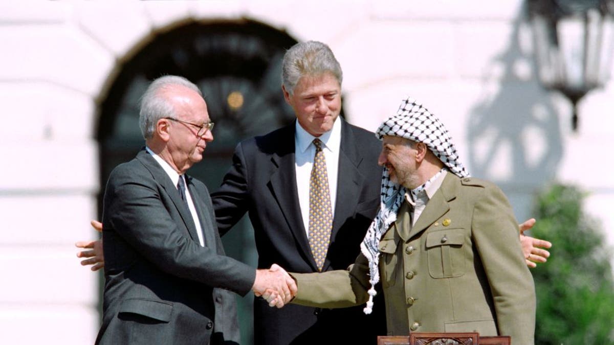 President Bill Clinton stands behind Yassar Arafat and Israeli Prime Minister Yitzhak Rabin