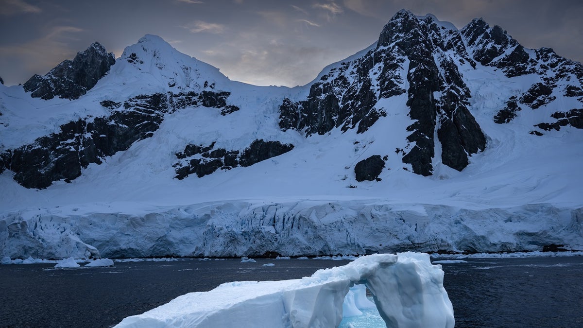 Iceberg near Antarctica, snowcapped mountains behind it