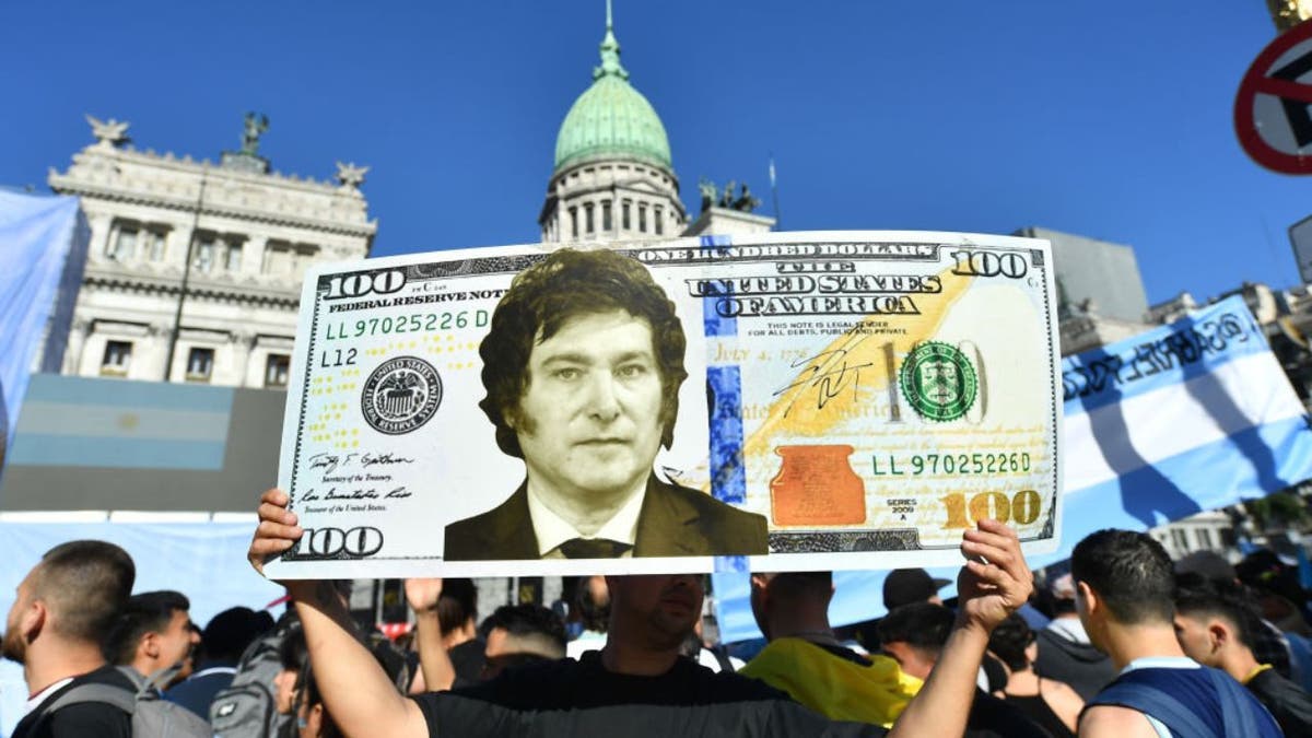 A man holds up a giant US dollar sign with President Argentina's President Javier Milei